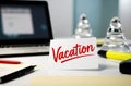 Ã¢â¬ÅVacationÃ¢â¬Â note on office desk. Laptop supplies, blurred background Royalty Free Stock Photo